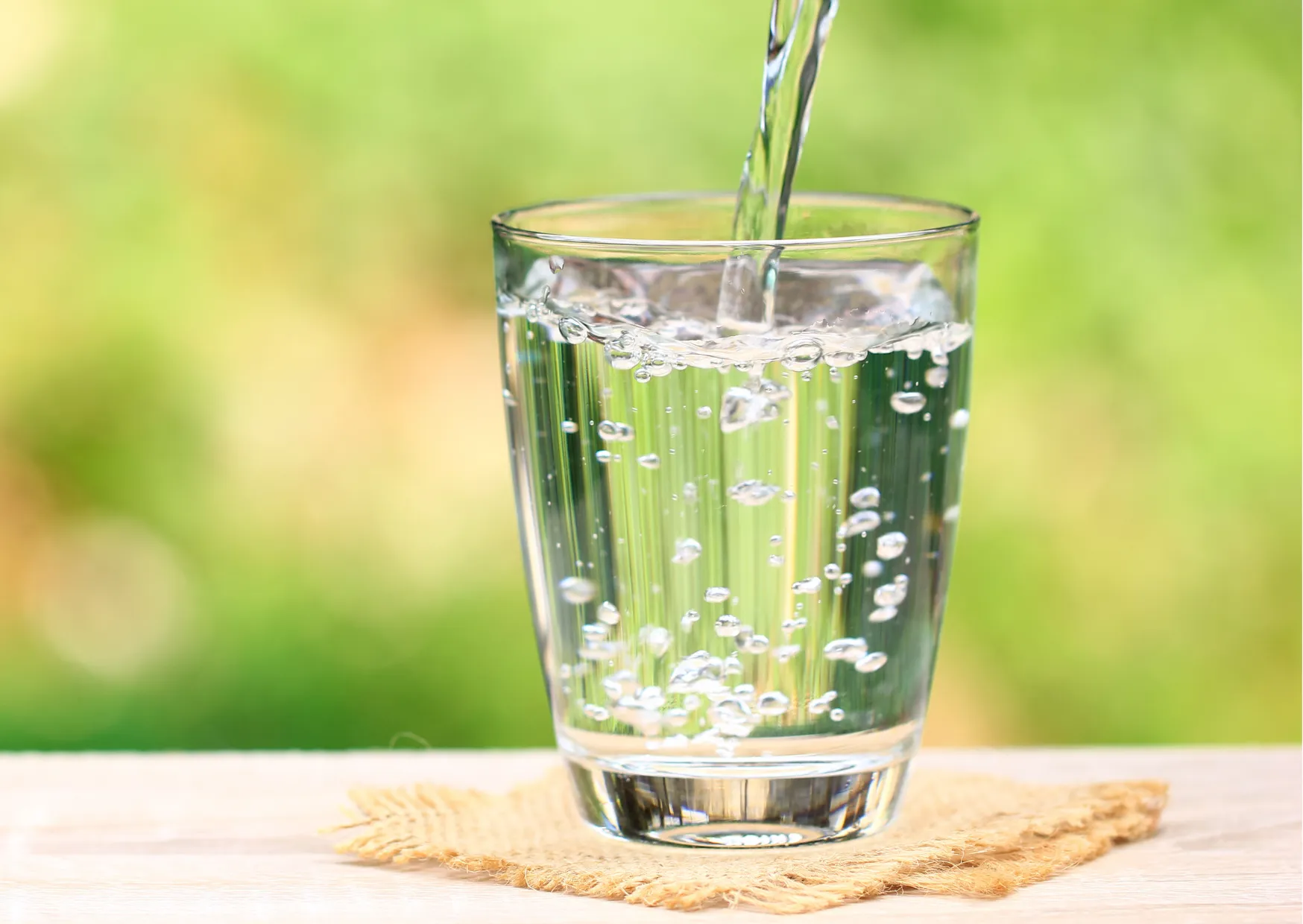 Sprudelndes Wasser wird in ein Glas gegossen, im Fokus steht die Trinkwasserqualität.