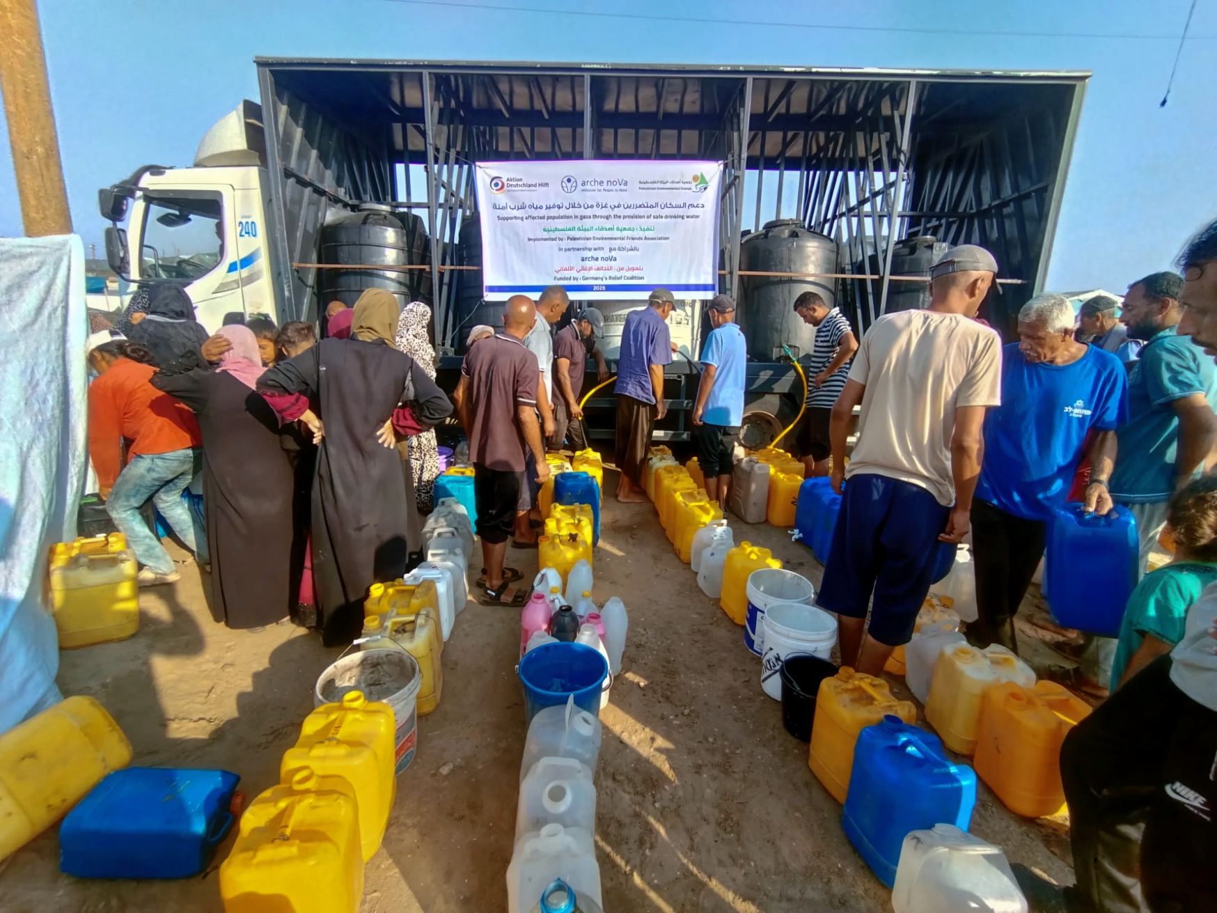Dutzende von Wasserkanistern reihen sich in Gaza vor einem Wassertank auf – arche noVa ermöglicht Zugang zu Trinkwasser