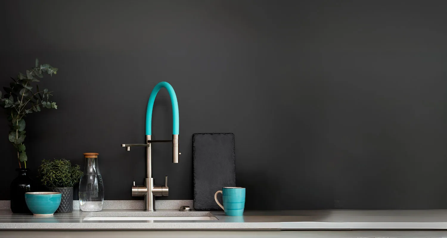 Moderne Küche mit einer Waschbeckenarmatur, einer blauen Tasse, einer Glasflasche und Pflanzen.