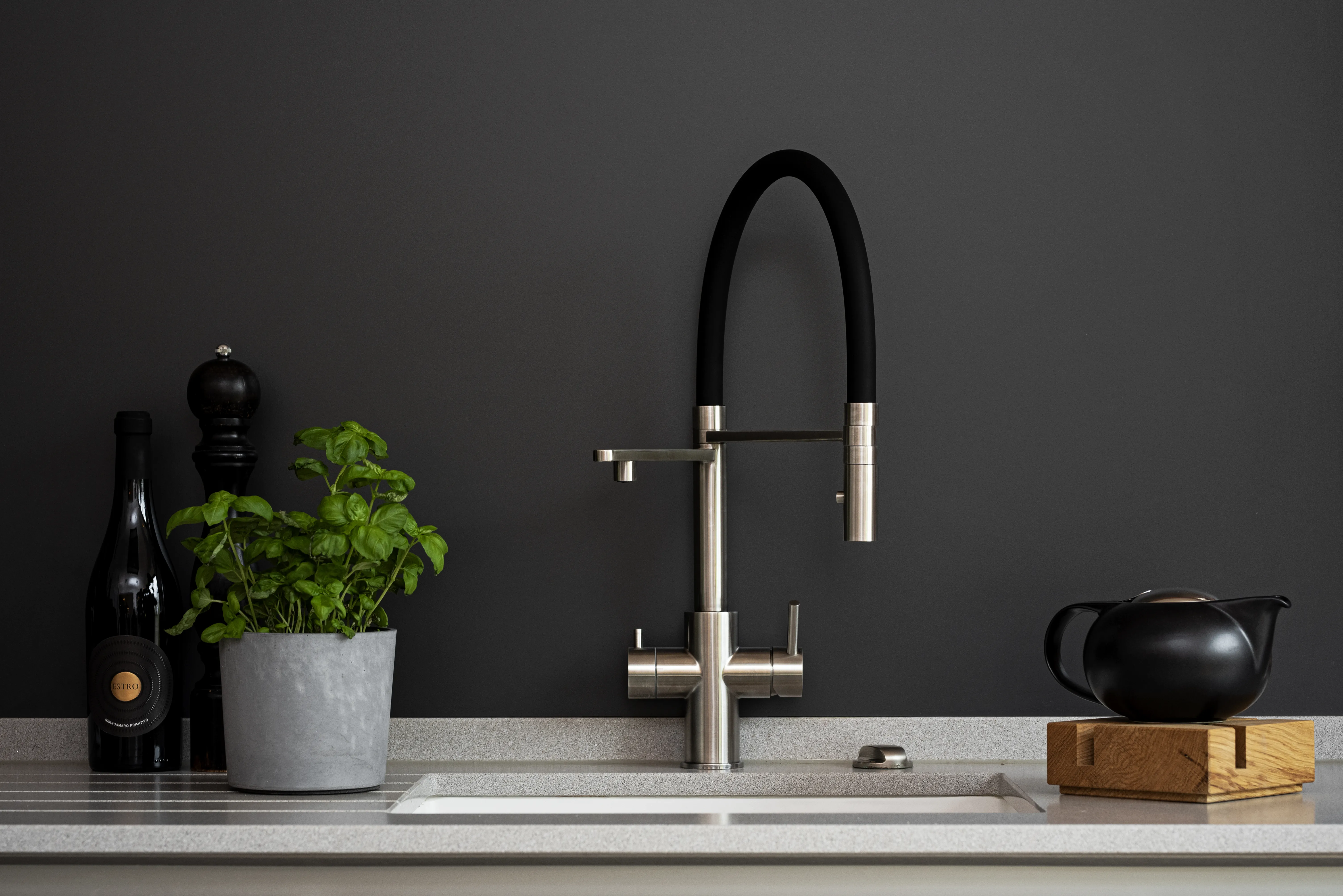 LivingTap Küchenarmatur in Edelstahloptik mit schwarzem Schlauch vor dunkler Wand