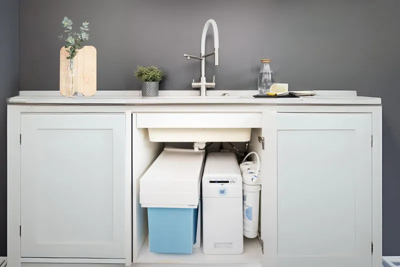 Moderne Kücheneinheit mit Spüle, Wasserhahn, Pflanzen und Wasserfiltersystem.