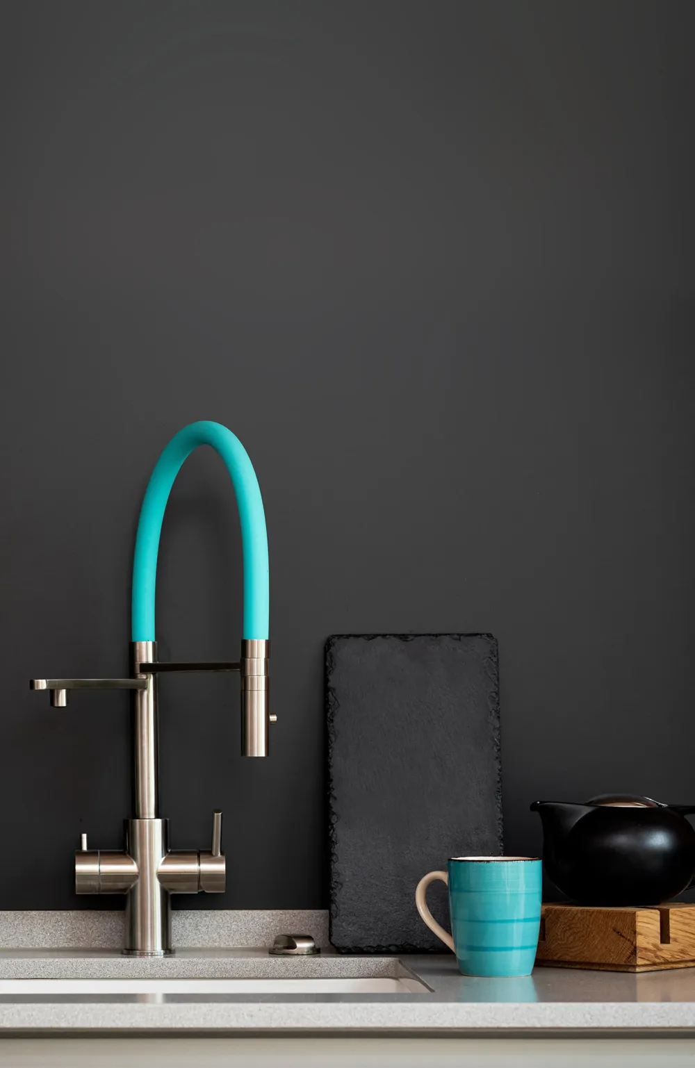 Moderne Küche mit einer Waschbeckenarmatur, einer blauen Tasse, einer Glasflasche und Pflanzen.