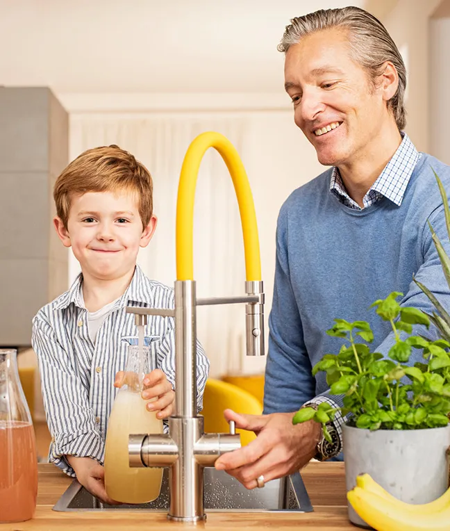 Familie nutzt modernen Wasserspender – ideal für Küche mit Kindern.
