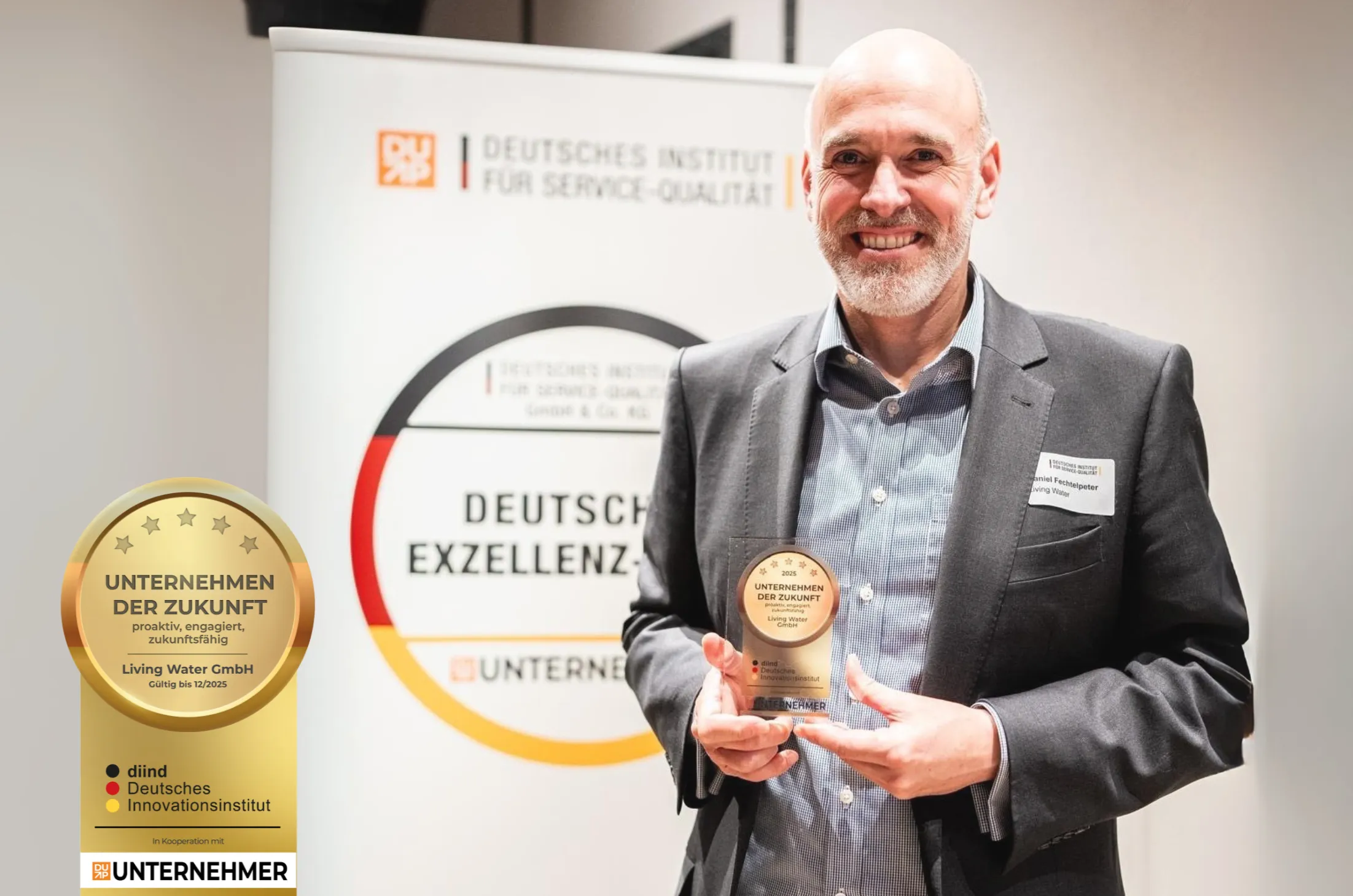 Ein Mann hält einen Preis in der Hand und lächelt. Im Hintergrund steht ein Banner des Deutschen Instituts für Service-Qualität. Der Preis ist für "Unternehmen der Zukunft".