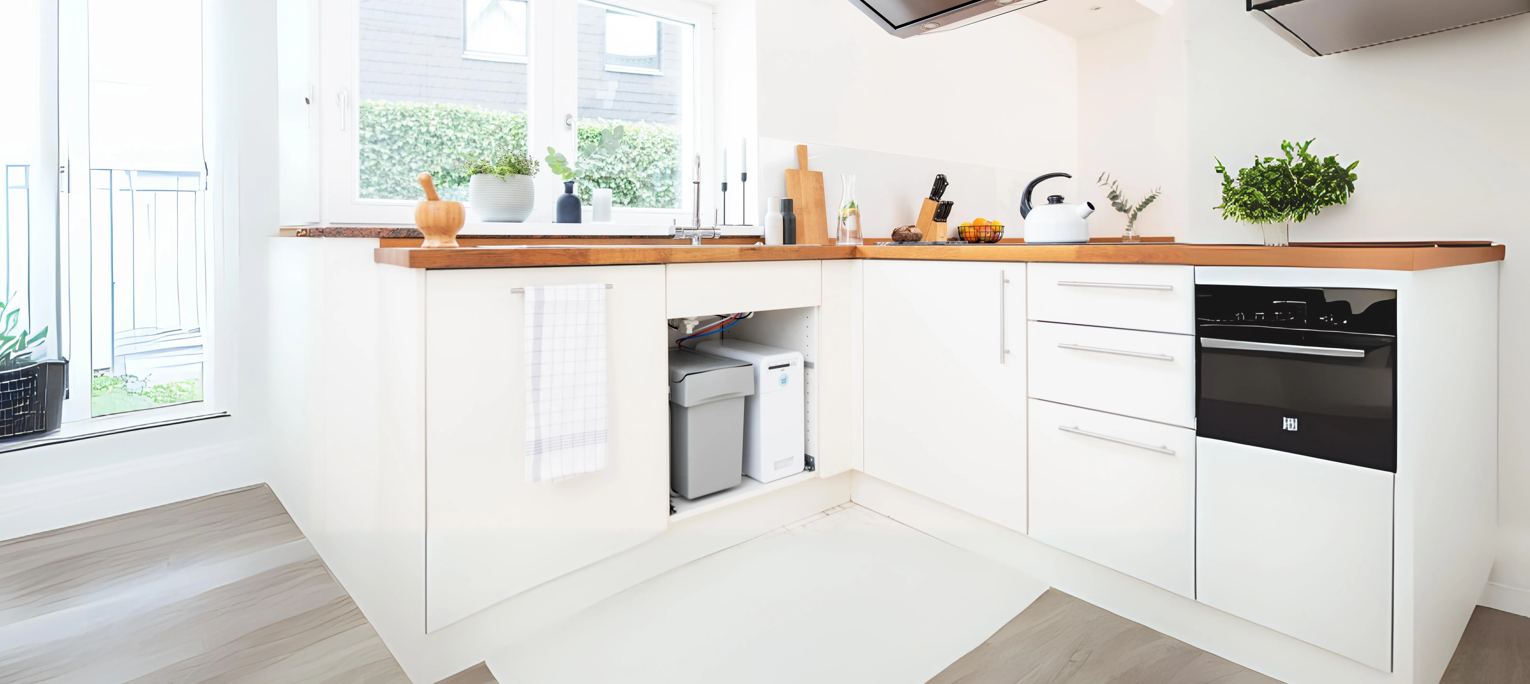 Moderne Küche mit weißen Schränken, Holzplatte, Spüle, Kochfeld und Fenstern.