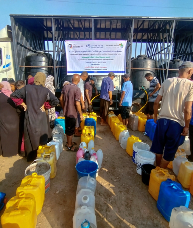 Zahlreiche Menschen in Gaza warten mit Kanistern auf dringend benötigtes Wasser von einem mobilen Versorgungspunkt.