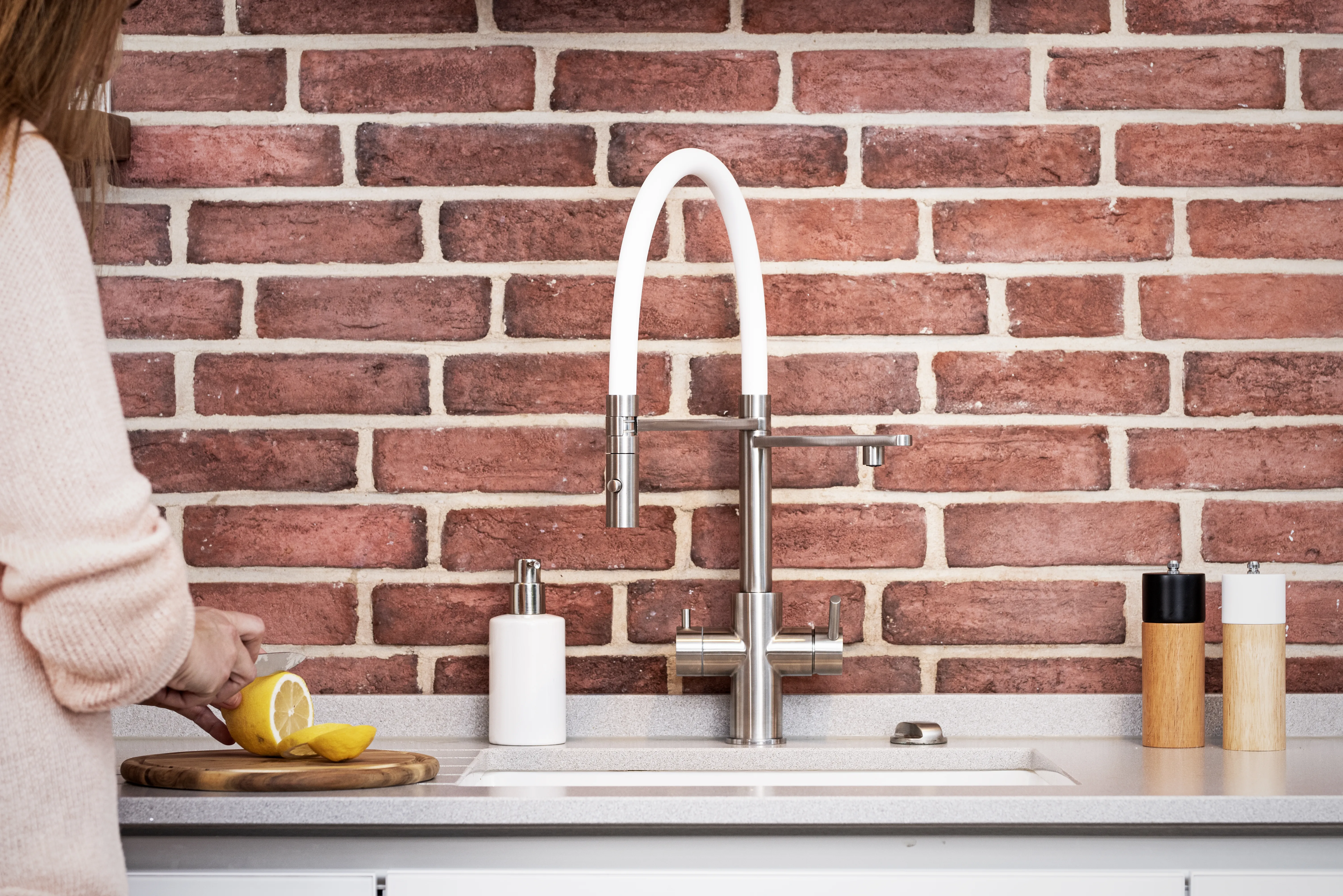 Küchenarmatur mit weißem Schlauch vor Ziegelwand